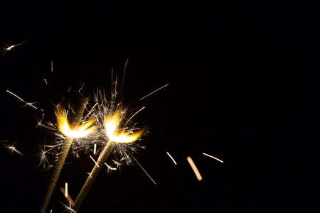 Two bright festive Christmas sparklers on black background with free spaceの写真素材