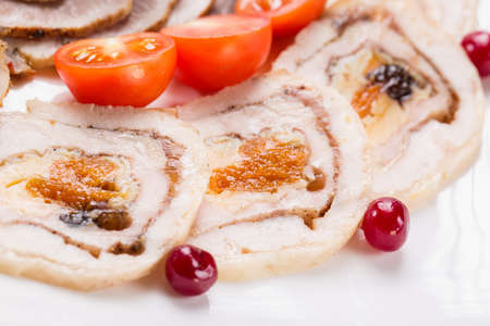 Meat rolls with cherry tomatoes and cranberry on white plate. Close up with selective focus.