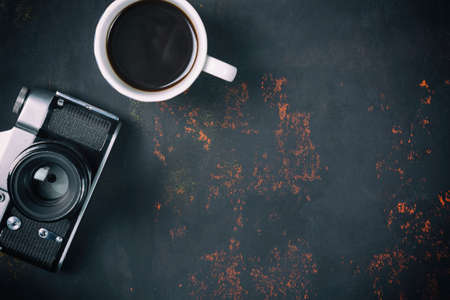 Top view a cup of coffee with vintage film camera on rusty stone background with free spaceの写真素材