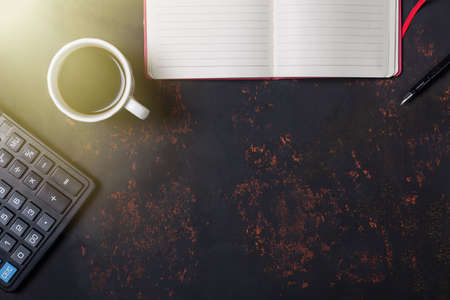 Top view a cup of coffee with notebook, fountain pen and calculator on rusty stone background with free space.の写真素材