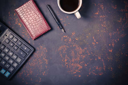 Top view a cup of coffee with leather notebook, fountain pen and calculator on rusty stone background with space for your text.の写真素材