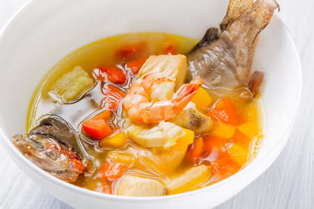 Fish soup with vegetables, shrimps and potatoes in white plate close up.の写真素材