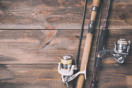Fishing rods and reels with line on wooden background with free space. Toned image.の写真素材