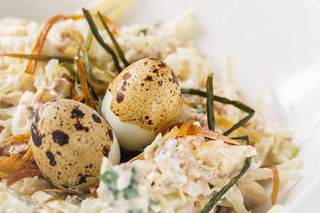 Vegetable salad with quail eggs and herbs on white plate with selective focus.の写真素材