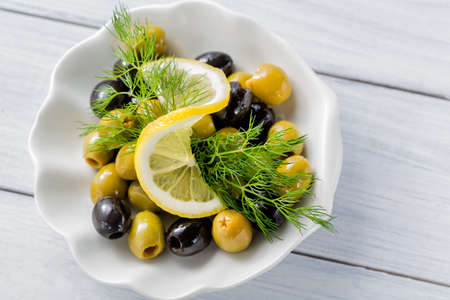 Sliced lemon with olives and dill on white wooden tableの写真素材