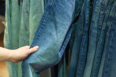 Hand of woman choosing jeans in the store. Selective focus.の写真素材
