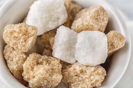 White sugar and brown sugar cane cube in white bowl on white background. Close up image.の写真素材