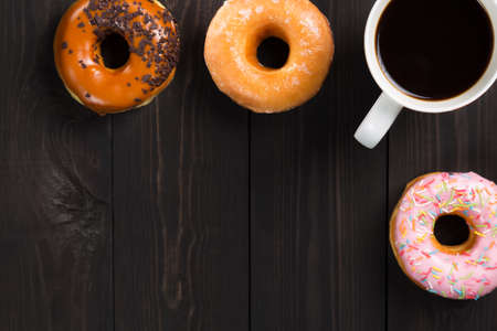 Cup with coffee and donuts on dark wooden table. Top view and free space for your text.の写真素材