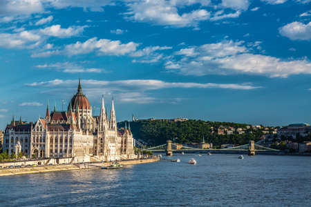 Travel and european tourism concept. Parliament and riverside in Budapest Hungary with sightseeing ships during summer sunny day with blue sky and clouds.の写真素材