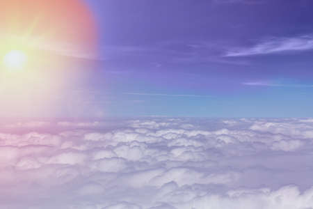 Clouds background with blue sky and sun during sunrise from above. View from airplane window.の写真素材