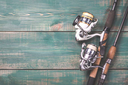 Fishing rods and reels with line on green wooden background with free space. Toned image.の写真素材