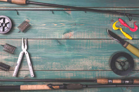 Fishing rods, fishing tackles, lines, knife and feeders on green wooden background with free space.の写真素材