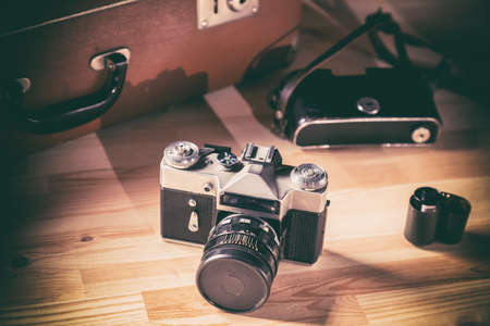 Old film camera with film against the background of a vintage brown suitcase.