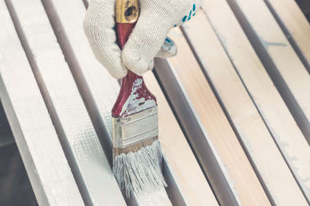 Hand in gloves holding brush and paint timber close up. Toned.の写真素材