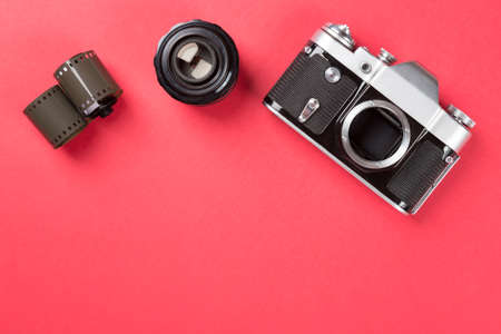 Old film camera with lens and film on red background. Top viewの写真素材