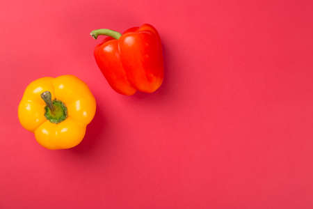 Top view of bright yellow and red bell peppers paprika on red backgroundの写真素材