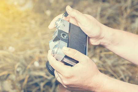 Woman hands are holding old vintage film camera outdoors. Tonedの写真素材