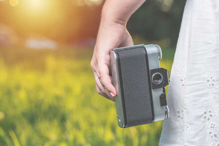 Woman hands are holding old vintage film camera outdoors. Tonedの写真素材