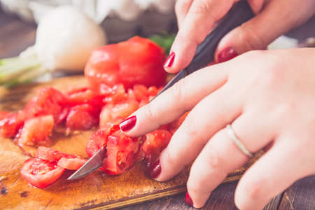 Woman hands cutting tomatoes with blurred vegetables in the background. Tonedの写真素材