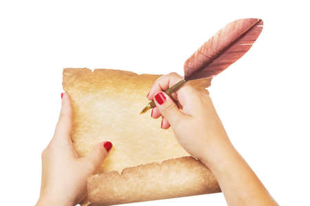 Female hand writing on old paper scroll and fountain pen with feather quill isolated on white backgroundの写真素材