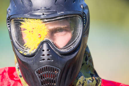 Portrait of a man with splash on helmet after direct hit in the paintball gameの写真素材
