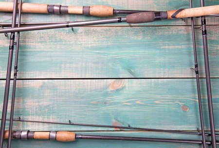 Fishing theme. Frame from fishing rods on green wooden background with free space inside