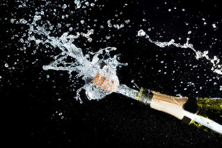 Celebration theme with explosion of splashing champagne sparkling wine on black background.の写真素材