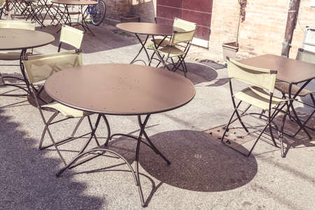 Empty street cafe in Italy under sunlight. Toned image.