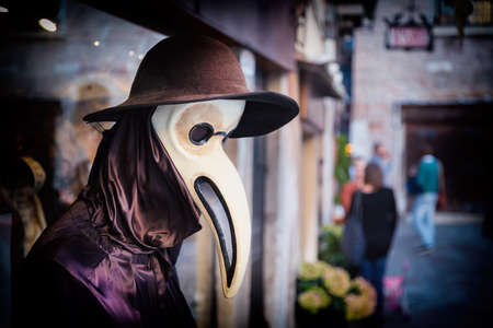 Traditional venetian mannequin in Plague doctor costume, mask and hat near shop window in the street of Venice, Italy. Toned imageの写真素材