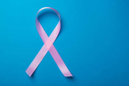Breast Cancer concept. Pink ribbon symbol of breast cancer on blue backgroundの写真素材