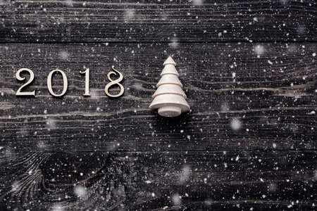Happy New Year 2018 of real wooden figures with a fir tree on dark wooden background with snowの写真素材