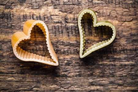 Two heart shaped italian pasta on wooden background.の写真素材