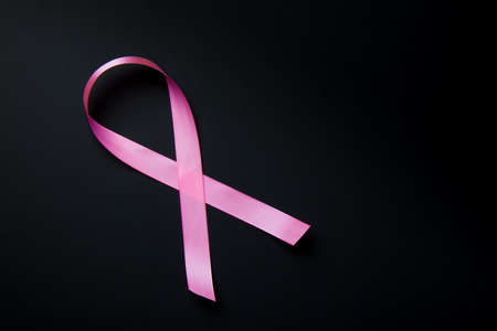 Breast Cancer concept. Pink ribbon symbol of breast cancer on black background