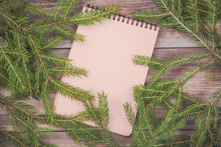 Message to Santa Claus. Christmas fir tree branches on wooden board with blank notebook. Christmas or new year frame for your project with copy space on the blank notebookの写真素材