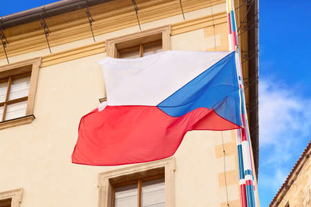 Waving Czech Republic Flag in Prague against house and blue sky.
