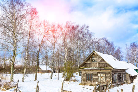 Winter landscape with old wooden house and trees with sunlight and blue cloudy sky. Amazing winter scene.の写真素材