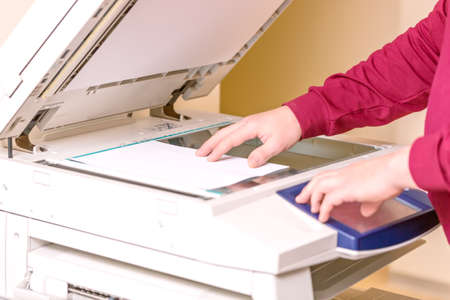 Man putting paper sheet on printer for scanning. Office work concept