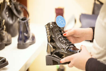 Woman looking for discounts and taking black shoe with a discount sign in store. Shopping concept. Selective focus.の写真素材