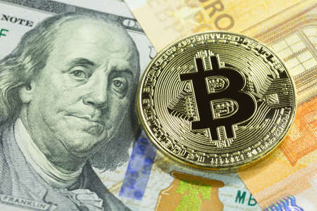 Golden bitcoin on 100 dollar and euro bills. Close up image. Cryptocurrency concept