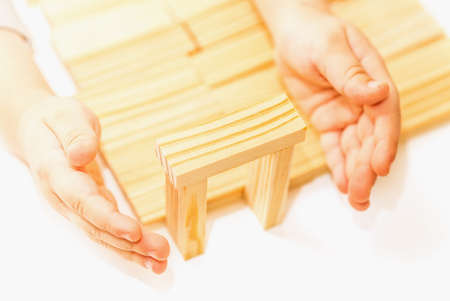 Female hands building small wooden house from wodden block for kids on white background. Household conceptの写真素材