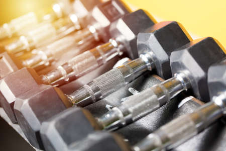 Fitness sports concept. Black dumbbell set. Close up many metal dumbbells on rack in sport fitness center. Toned image with selective focus.の写真素材