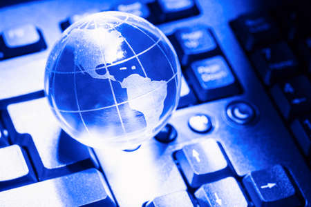 World transparent globe earth on computer keyboard. Global communications business concept. Blue tonedの写真素材