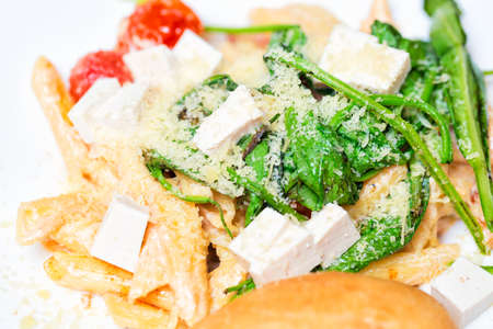 Italian pasta with cheese, tomatoes and herbs on white plate. Close up with selective focusの写真素材