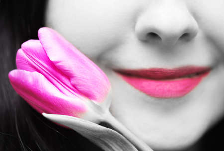 Nature or spring background. Young woman brunette with purple colored lips and purple tulip on black...