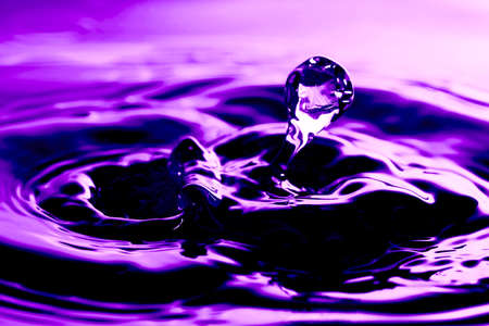 Water drop and ripples shot on niceultraviolet purple background. Artistic nature abstract image