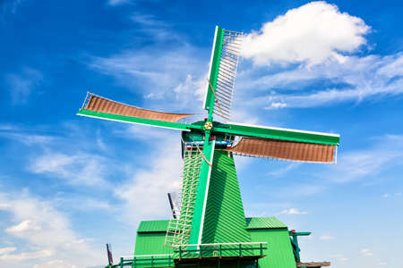 Dutch typical landscape. Traditional old dutch windmill against blue cloudy sky in the Zaanse Schans village, Netherlands. Famous tourism placeの写真素材