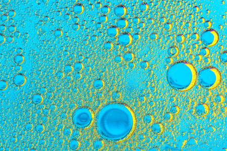 Water bubbles on blue and yellow background. Scientific image of cell membrane. Macro up of liquid...
