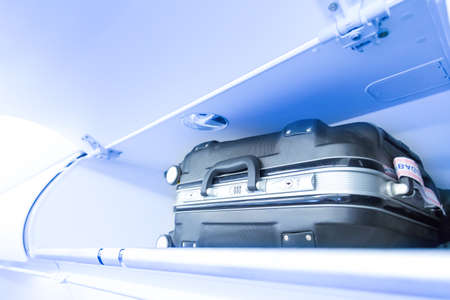 Luggage shelf with luggage suitcase in an airplane. Aircraft interior. Travel conceptの写真素材