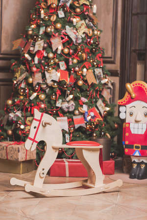 Christmas room decoration interior with horse chair, new year tree and nutcracker. Toned effect.
