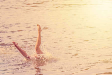 Girl falling jumping into the water with splash. Recreation concept. Toned imageの写真素材